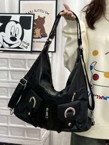 Detailed view of black faux leather multi-pocket hobo shoulder bag with metal ring buckles.