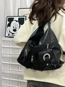 Detail view of a black multi-pocket PU leather backpack featuring stylish metal rings and zippers.