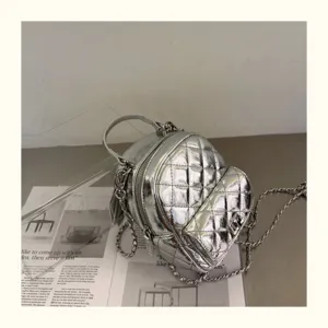 Mini sac à dos matelassé métallisé argenté avec bretelles chaînées, détail de mode chic.