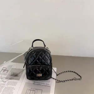 Détail du mini sac à dos matelassé noir avec chaîne argentée et texture en cuir.