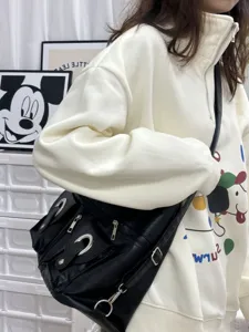 Black leather shoulder bag with metal ring hardware and multiple zipper pockets for daily use.