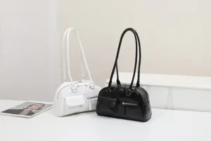 Detail view of retro shoulder bags in black and white with dual straps and front pockets.