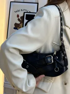 Close-up detail of a black leather motorcycle shoulder bag with metal buckles and hardware.