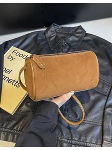 Detailed shot of brown suede cylindrical crossbody bag texture and metal zipper hardware.