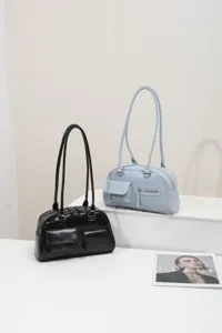 Detailed view of minimalist women shoulder bags in black and light blue displayed on white stand.