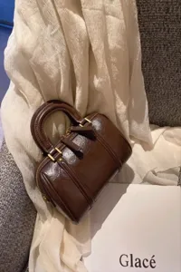 Brown patent leather Boston handbag detail, retro design with dual handles and gold zipper.