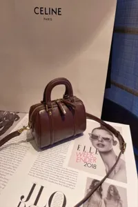 Brown leather Boston bag detail showing vintage texture, dual handles and shoulder strap.