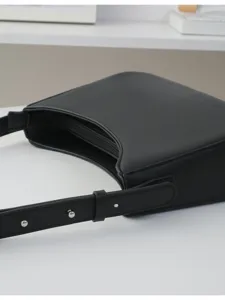 Black minimalist underarm shoulder bag detail, sleek leather texture with silver hardware.