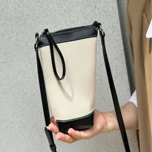 Chic canvas bucket bag with black leather trim and crossbody strap for daily casual wear.
