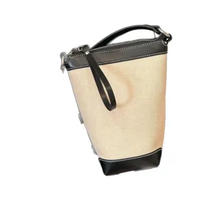 Casual canvas bucket bag with black leather trim, stylish crossbody handbag for women.