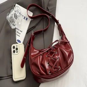 Red patent leather shoulder bag with lace-up bow, trendy crescent dumpling bag for women.