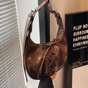 Brown patent leather hobo shoulder bag with stylish bow lace-up design for women daily wear.