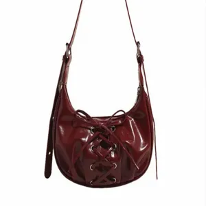 Red patent leather pleated underarm shoulder bag with bow lace-up design for women.