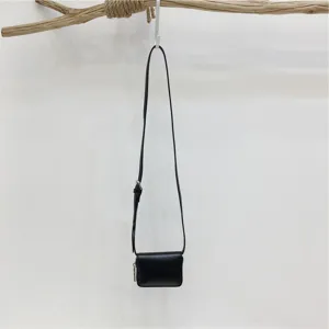 Detailed view of a minimalist black mini crossbody bag, small shoulder purse and card wallet.