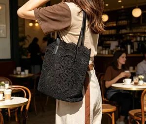 Vue détaillée d'un sac cabas en dentelle noire avec poignées en cuir, grand et élégant.