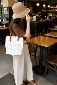 Vue détaillée du sac fourre-tout en dentelle blanche élégante avec anses en cuir marron.