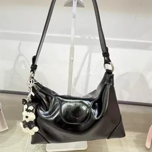 Close-up detail of the black glossy pleated dumpling bag with cute puppy charm and strap.