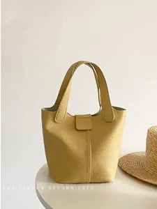 Close-up detail view of a yellow PU leather bucket bag, casual handbag with top handles.