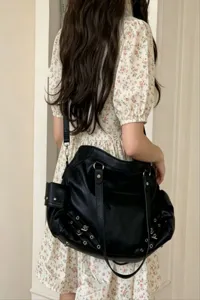 Detail shot of black PU leather shoulder bag with metal grommets and large capacity style.