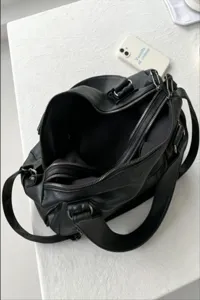 Detailed view of black leather travel duffel bag, multiple zippers, large capacity design.