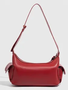 Red shoulder bag detailed view featuring crescent shape, side pockets, and adjustable strap.