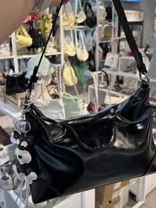 Black glossy pleated dumpling shoulder bag with cute dog pendant and chic motorcycle style.