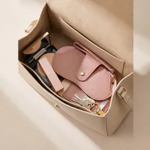 Detail view of portable leather sunglasses case and makeup storage bag in elegant beige tone.