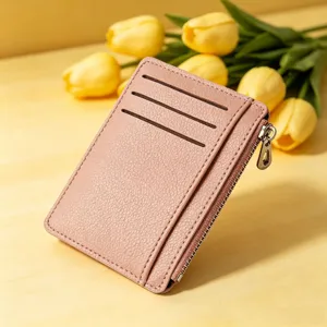 Vista dettagliata di un porta carte in pelle testurizzata rosa con fessure e tasca con zip.