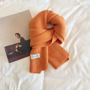 Detail view of orange knit scarf, cozy winter wool neck warmer on clean white background.
