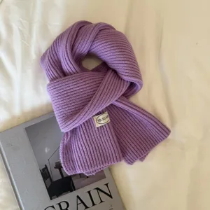 Detail shot of a minimalist solid color knitted wool scarf in purple, soft ribbed texture styling.