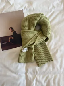 Green knitted scarf detail showcasing soft wool texture and minimalist winter warmth.