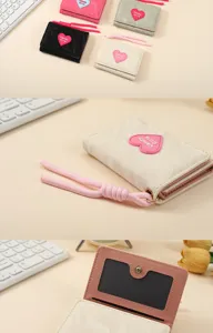 Detailed view of the cute trifold women's wallet with heart charm and lanyard accessory.