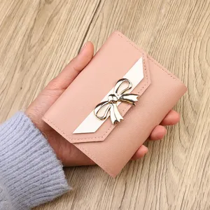 Pink trifold mini wallet for women with cute metal bow, compact card holder and coin purse.