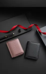 Close-up detail view of textured carbon fiber zipper wallets in black and rose gold.