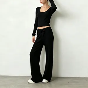 Black ribbed two-piece yoga set featuring a scoop neck long sleeve crop top and loose pants.