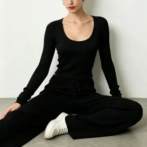 Detail view of black ribbed yoga set, featuring scoop neck long sleeve top and wide leg pants.
