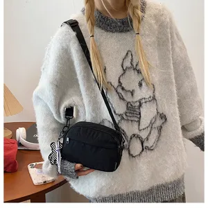 Vue détaillée d'un sac bandoulière noir décontracté et élégant avec pendentif ours.
