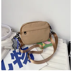 Vue detaillee du sac bandouillere en nylon decontracte avec sangle et joli charm ours.