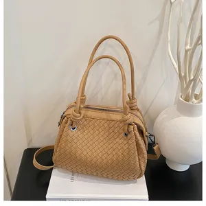 Detail view of woven leather handbag featuring knot handle design, elegant texture and structure.