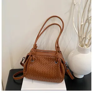 Detailed view of brown woven leather shoulder bag with knot handle and metal rings on display.