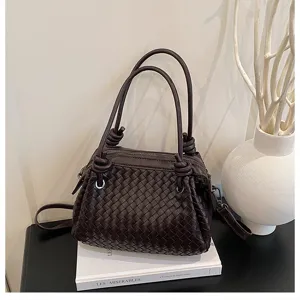 Detailed view of dark brown woven leather handbag featuring unique metal rope knots and handles.