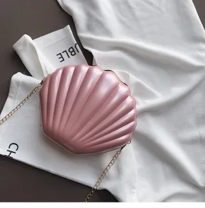 Dettaglio borsa a tracolla a conchiglia in pelle verniciata rosa con catena elegante.