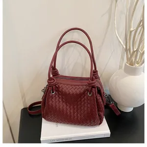 Exquisite woven leather handbag detail featuring stylish knot handles and rich burgundy tone.