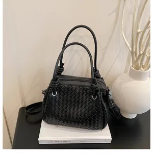 Black woven leather handbag detail shot featuring intricate grid pattern and stylish knot handles.