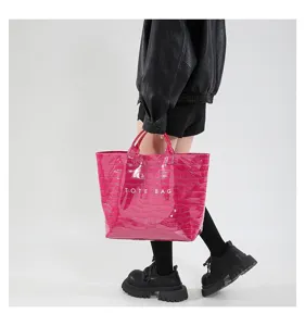 Nahaufnahme der stilvollen pinken Kroko-Optik Handtasche zeigt feine Textur und Griffe.