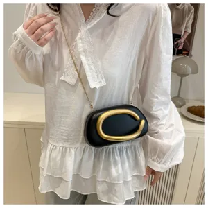 Élégant mini sac rond noir avec accessoire en métal doré en forme de lettre C et chaîne.