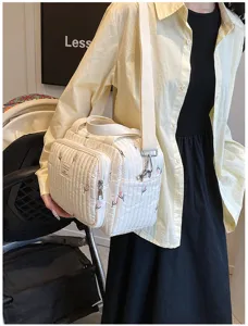 Primer plano detallado del bolso bandolera acolchado blanco con bordado de tulipanes, suave textura.