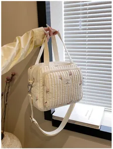 Primer plano del bolso cambiador acolchado con bordado de tulipán y textura de tela fina.