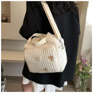 Vista detallada del bolso cambiador acolchado con bonitos osos bordados y etiqueta tejida.