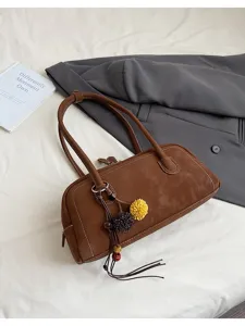 Detail view of brown vintage baguette shoulder bag with flower tassel charm and retro design.